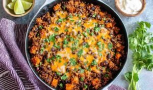 Mexican Quinoa Skillet with sweet potatoes, black beans, melted cheddar cheese, and fresh cilantro in a large skillet