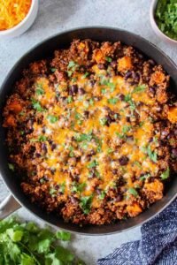 Mexican Quinoa Skillet with sweet potatoes, black beans, melted cheddar cheese, and fresh cilantro in a large skillet