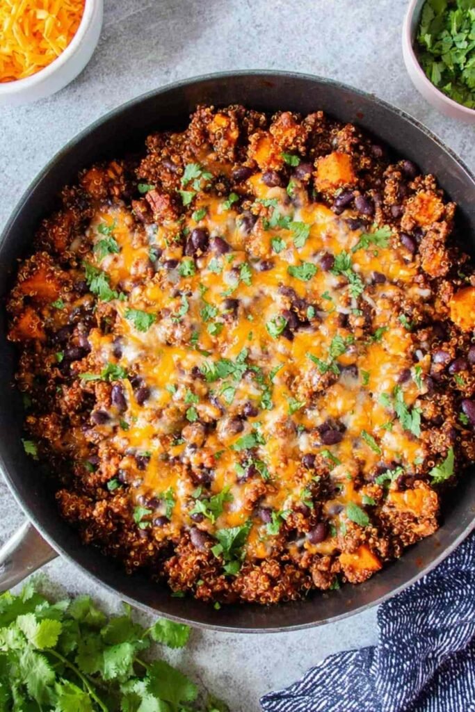 Mexican Quinoa Skillet with sweet potatoes, black beans, melted cheddar cheese, and fresh cilantro in a large skillet