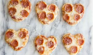 Mini heart shaped pizzas with bubbly melted mozzarella and heart-cut pepperoni fresh from the oven