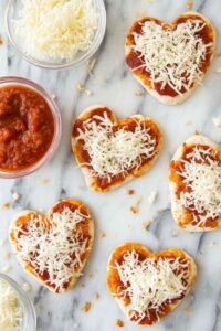 Mini heart shaped pizzas with bubbly melted mozzarella and heart-cut pepperoni fresh from the oven