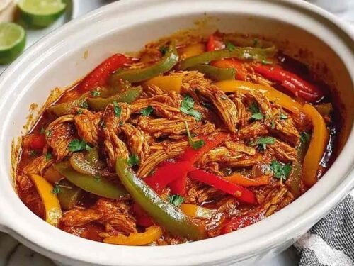 Mediterranean chicken tenders on a white plate garnished with fresh parsley and lemon wedges