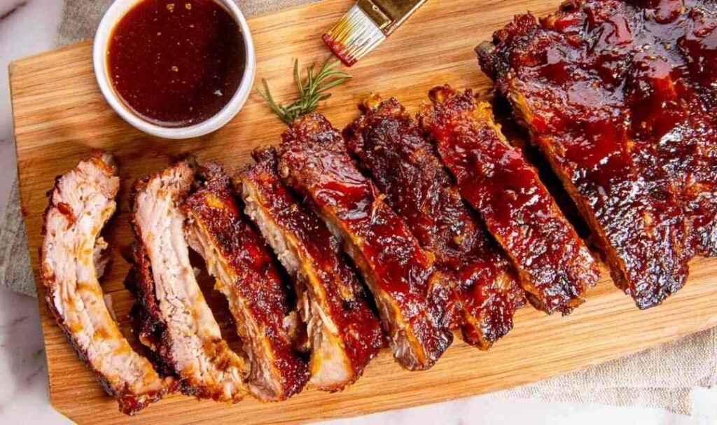 Rack of oven baked ribs sliced and coated in caramelized BBQ sauce on a cutting board