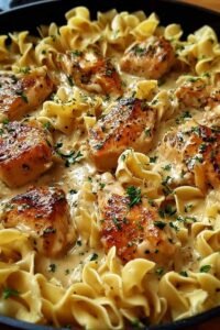 One pan creamy garlic butter chicken with egg noodles in a large skillet garnished with fresh parsley and Parmesan cheese