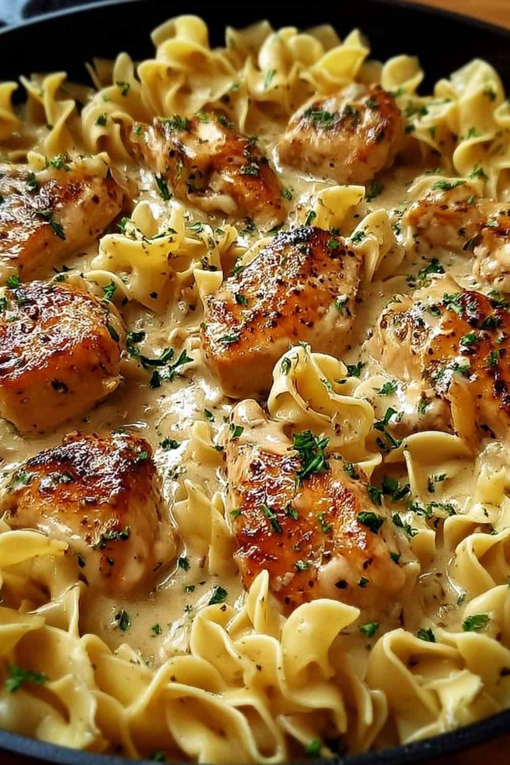 One pan creamy garlic butter chicken with egg noodles in a large skillet garnished with fresh parsley and Parmesan cheese