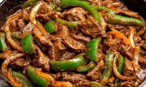 Pepper steak with tender ribeye strips, colorful bell peppers, and rich tomato beef sauce served over white rice with fresh green onion garnish