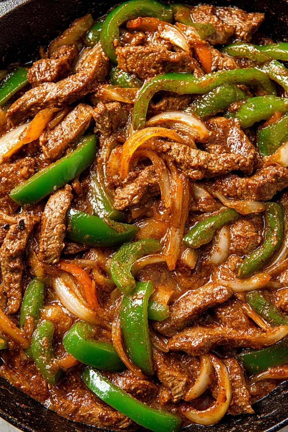 Pepper steak with tender ribeye strips, colorful bell peppers, and rich tomato beef sauce served over white rice with fresh green onion garnish