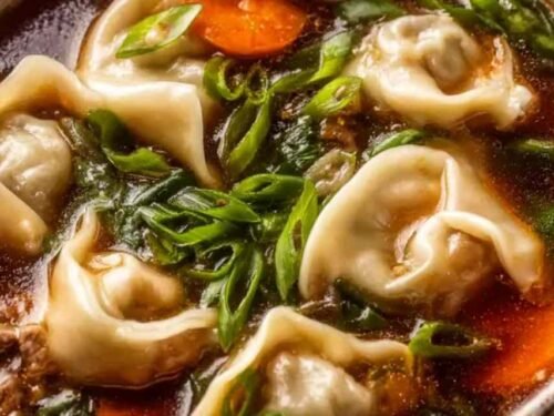 Potsticker soup in a bowl with beef dumplings, fresh greens, and chopped green onion garnish