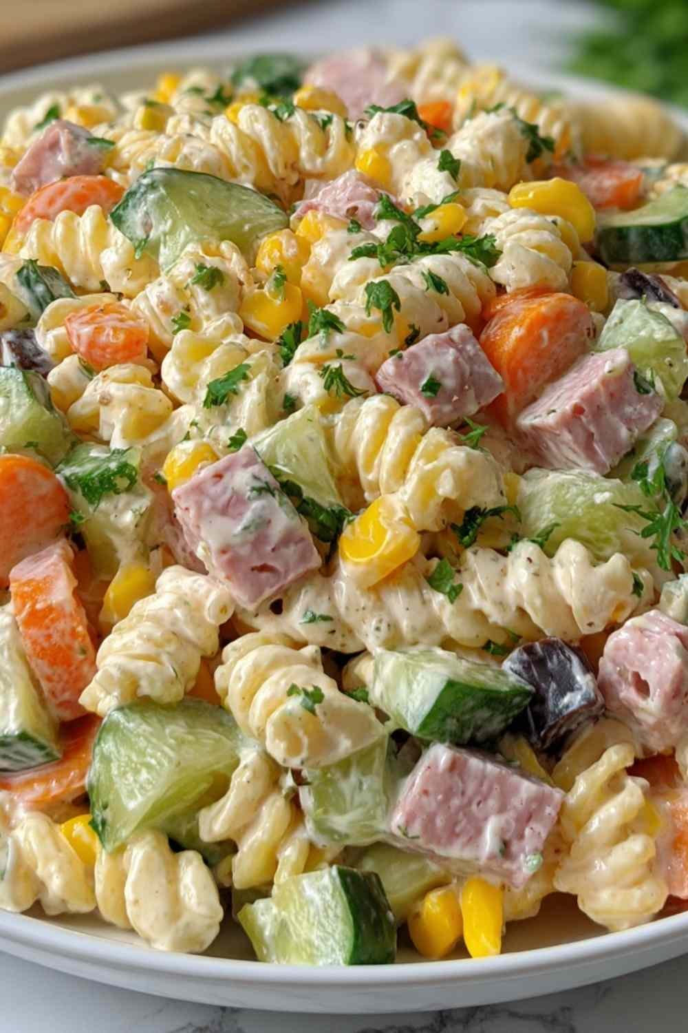 Creamy cold pasta salad with rotini, bell peppers, corn, and carrots in a large white serving bowl