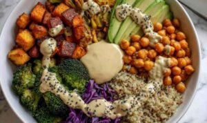 Colorful vegan Buddha bowl with quinoa, chickpeas, roasted sweet potato, broccoli, and tahini dressing