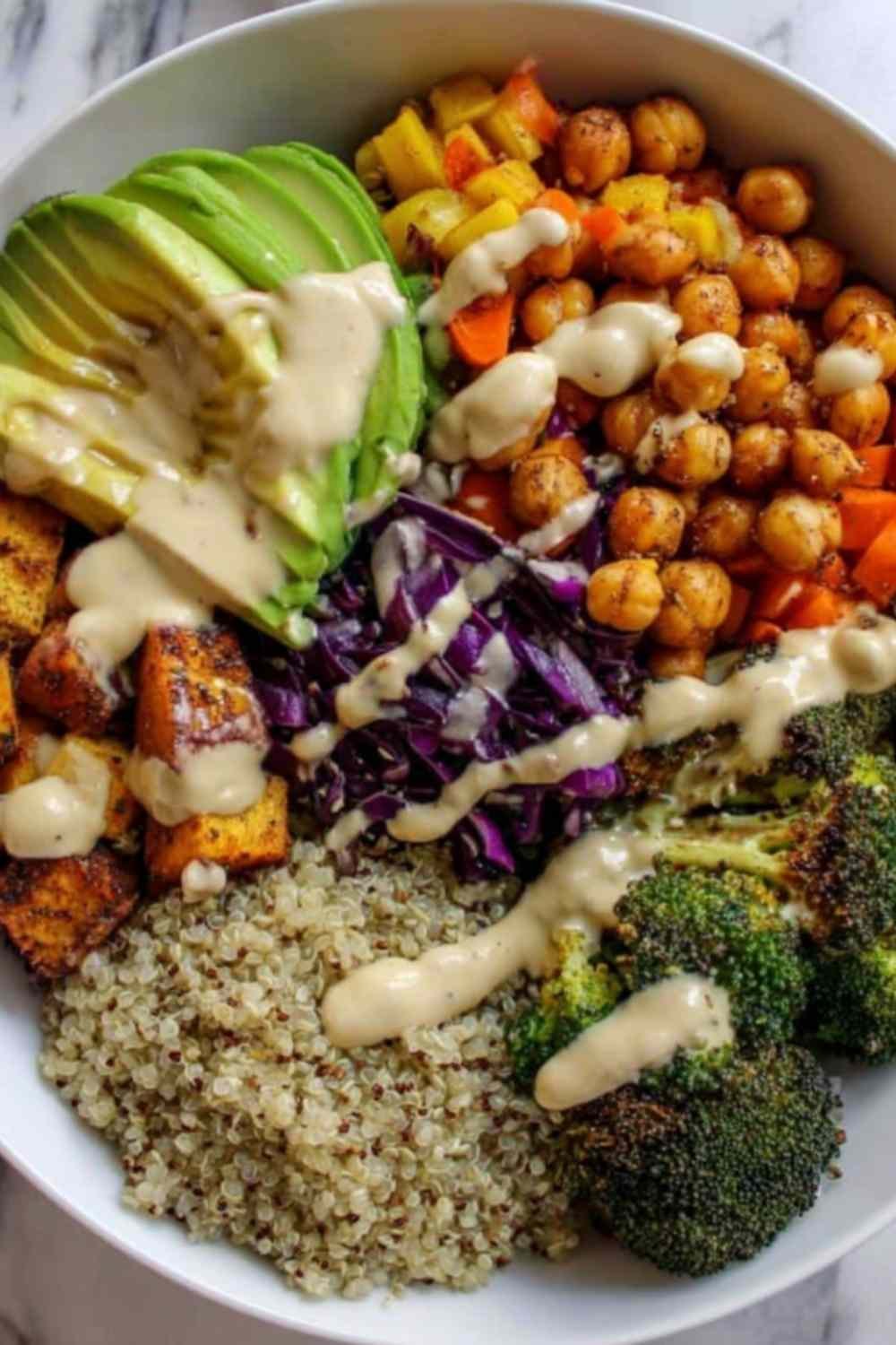 Colorful vegan Buddha bowl with quinoa, chickpeas, roasted sweet potato, broccoli, and tahini dressing