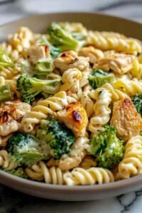 Creamy rotisserie chicken broccoli pasta in a white bowl with Parmesan sauce, tender shredded chicken, and broccoli florets