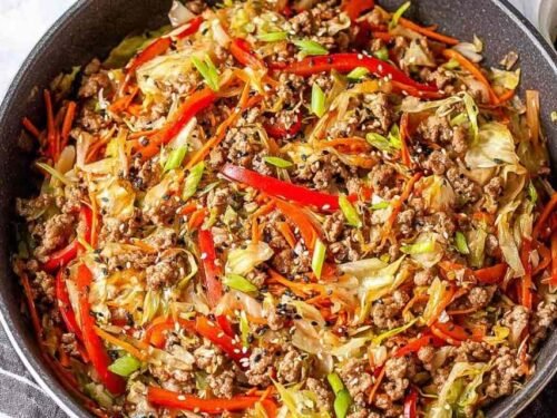 Egg roll in a bowl with ground turkey, cabbage, carrots, and sesame seeds in a large skillet