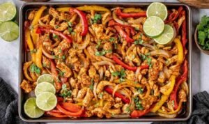 Sheet Pan Chicken Fajitas Sheet pan chicken fajitas with colorful bell peppers and caramelized onions on a parchment-lined rimmed baking sheet