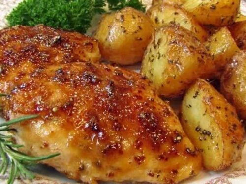 Sheet pan chicken and potatoes with honey garlic glaze, golden baked chicken breasts and roasted baby Yukon gold potatoes on a foil-lined baking sheet