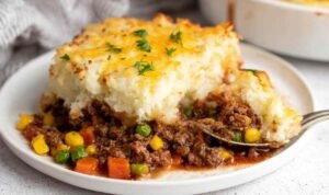 The Best Shepherd's Pie Recipe Shepherd's pie in a white baking dish with golden mashed potato topping and bubbling beef filling at the edges