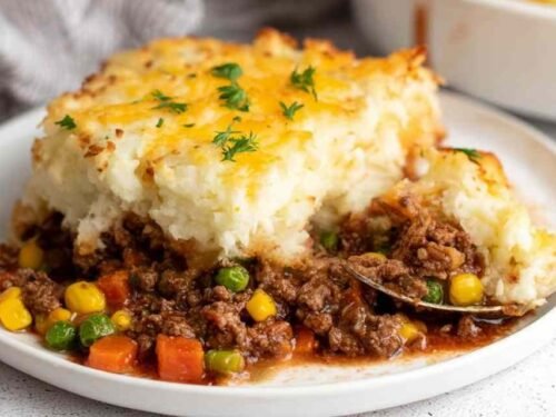 Shepherd's pie in a white baking dish with golden mashed potato topping and bubbling beef filling at the edges