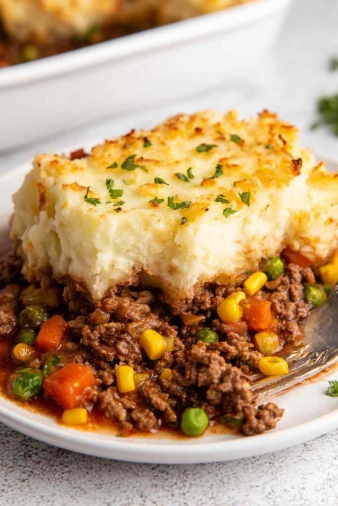 Shepherd's pie in a white baking dish with golden mashed potato topping and bubbling beef filling at the edges