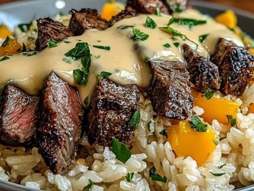Steak and queso rice served hot in a cast iron skillet topped with fresh cilantro, sour cream, and avocado slices