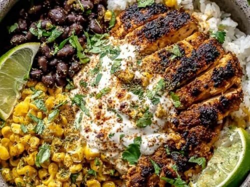 Street corn chicken rice bowl with charred corn, sliced chicken thighs, cotija cheese, and lime crema over cilantro rice