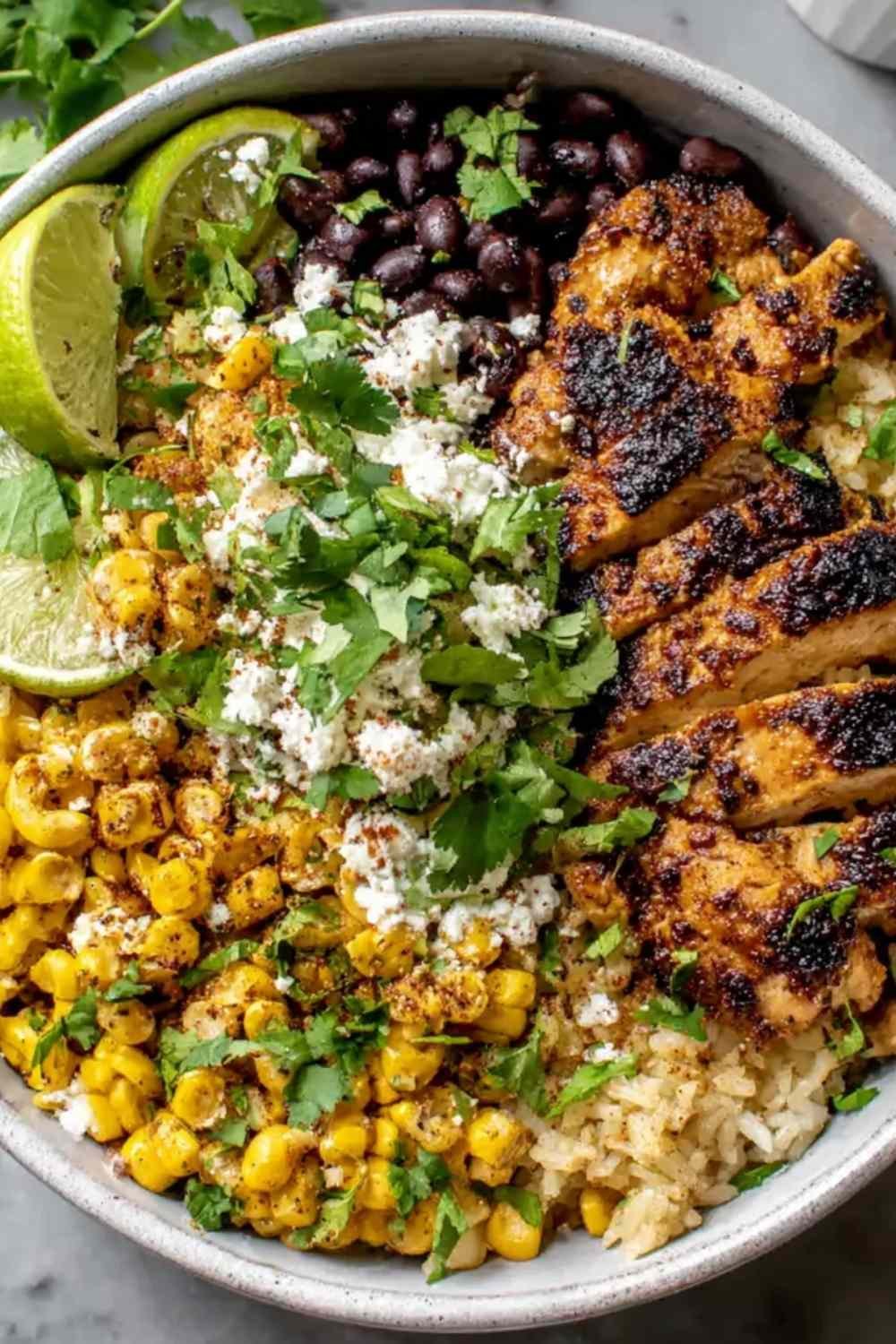Street corn chicken rice bowl with charred corn, sliced chicken thighs, cotija cheese, and lime crema over cilantro rice