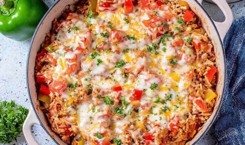 Stuffed pepper casserole in a large skillet topped with melted cheese and fresh parsley