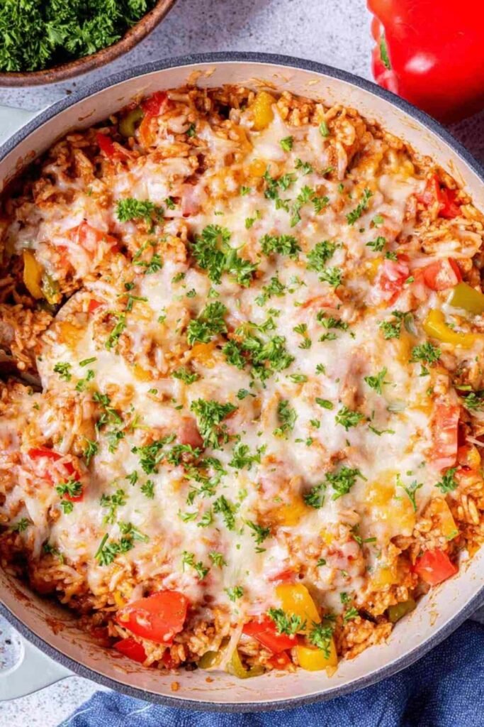 Stuffed pepper casserole in a large skillet topped with melted cheese and fresh parsley