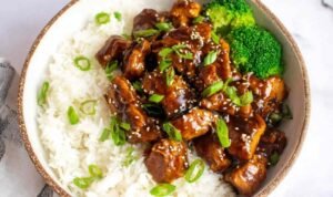 Homemade teriyaki chicken served over white rice with broccoli and sesame seeds