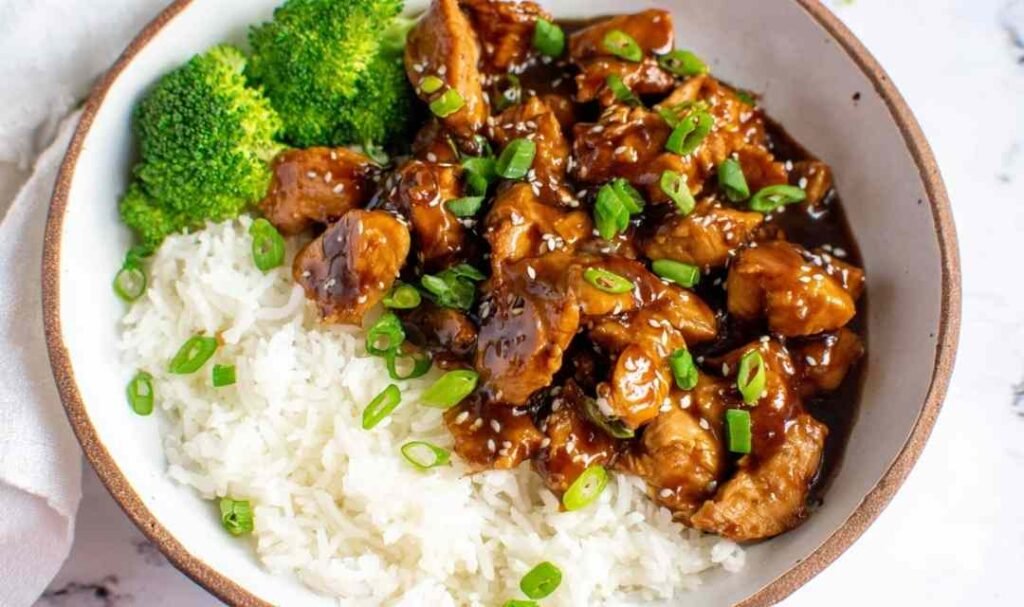 Homemade teriyaki chicken served over white rice with broccoli and sesame seeds