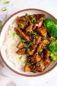 Homemade teriyaki chicken served over white rice with broccoli and sesame seeds
