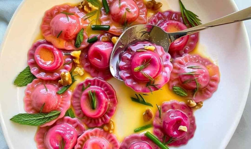 Valentine's Day ravioletti with pink beet pasta served in silky butter sauce with toasted walnuts and fresh mint and dill on a white plate