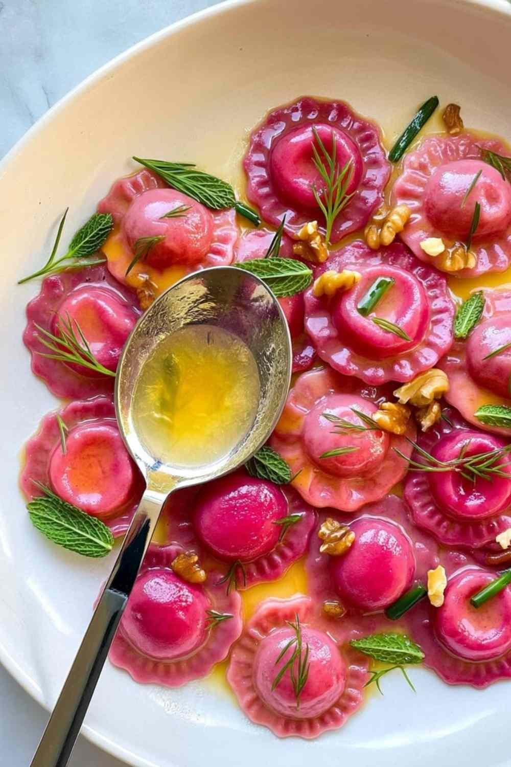 Valentine's Day ravioletti with pink beet pasta served in silky butter sauce with toasted walnuts and fresh mint and dill on a white plate