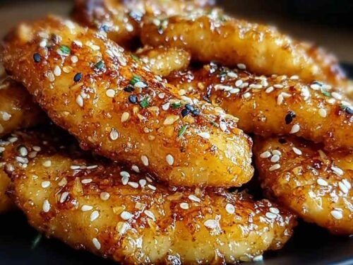 Raw chicken tenders being coated in honey butter garlic mixture and pressed into panko breadcrumbs before going into the air fryer basket
