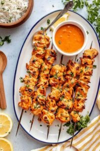 Baked apricot chicken skewers with caramelized glaze on a wire rack garnished with fresh parsley and green onions