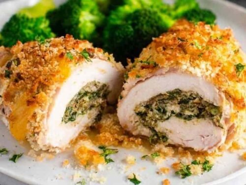 Baked Chicken Kiev sliced open on a white plate showing melted herb butter center with golden Panko crust