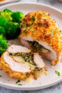 Baked Chicken Kiev sliced open on a white plate showing melted herb butter center with golden Panko crust