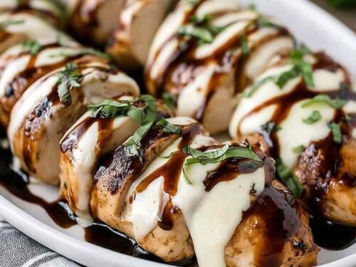 Balsamic baked chicken breast with mozzarella cheese and cherry tomatoes served in a white baking dish