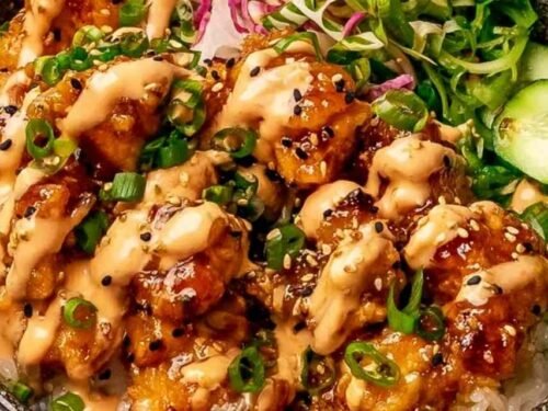 Bang bang chicken bowl with crispy chicken, jasmine rice, cucumber, carrots, and bang bang sauce drizzle overhead