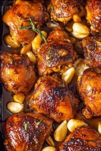 Crispy beer chicken thighs searing in a cast iron skillet with golden skin and garlic honey beer sauce
