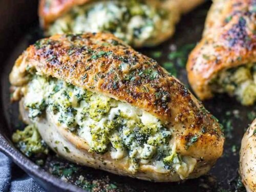 Broccoli cheese stuffed chicken breast sliced open on a white dinner plate showing creamy cheddar and broccoli filling