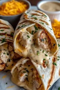 Cheesy Garlic Chicken Wraps sliced diagonally on a wooden board showing melty cheese and colorful vegetable filling