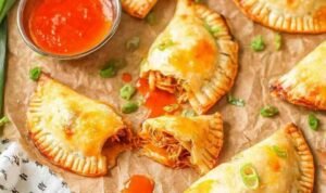 Golden baked chicken empanadas on a parchment-lined baking sheet fresh from the oven