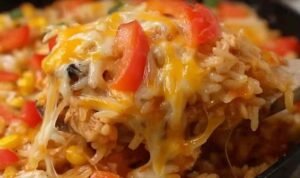 Chicken fajita rice casserole in a white baking dish with melted cheese, colorful bell peppers, and seasoned chicken