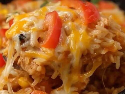 Chicken fajita rice casserole in a white baking dish with melted cheese, colorful bell peppers, and seasoned chicken