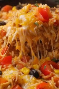 Chicken fajita rice casserole in a white baking dish with melted cheese, colorful bell peppers, and seasoned chicken
