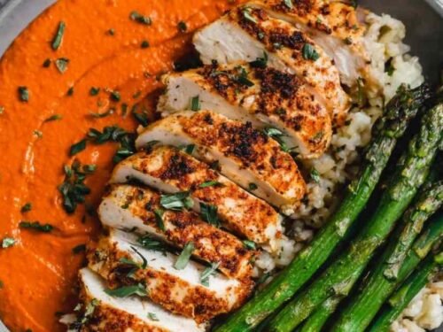Chicken romesco recipe with juicy baked chicken breast topped with smoky roasted red pepper almond sauce on a white dinner plate