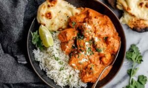 Chicken tikka masala in a non-stick pan with rich creamy orange tomato sauce, tender chicken pieces, and fresh cilantro garnish