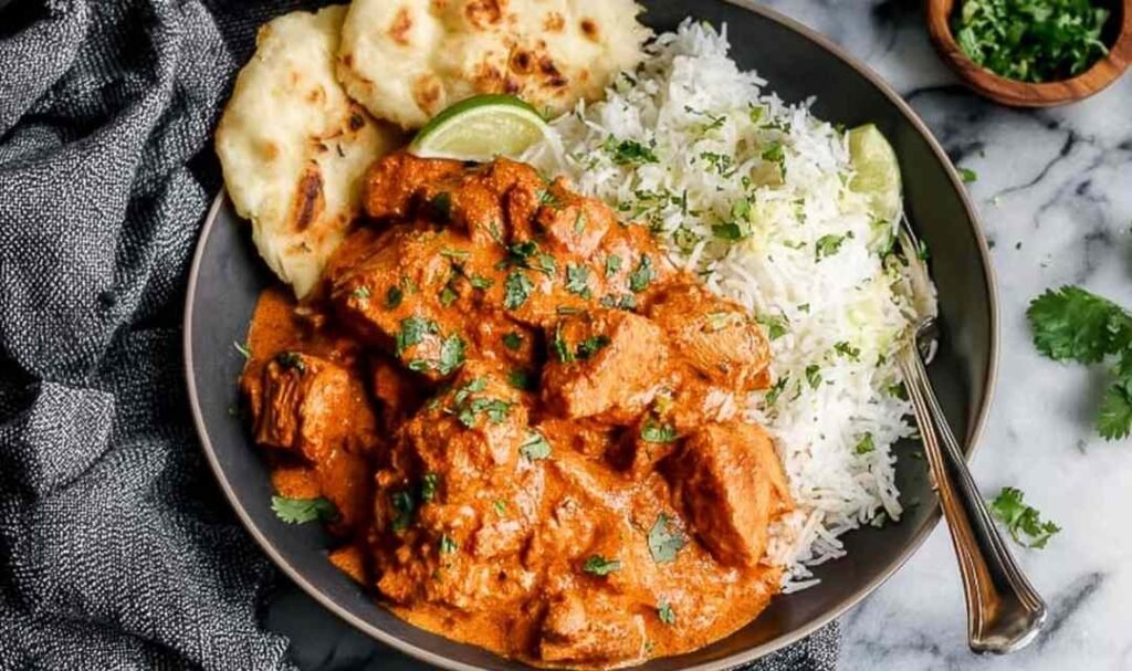 Chicken tikka masala in a non-stick pan with rich creamy orange tomato sauce, tender chicken pieces, and fresh cilantro garnish