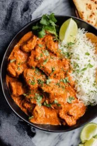 Chicken tikka masala in a non-stick pan with rich creamy orange tomato sauce, tender chicken pieces, and fresh cilantro garnish