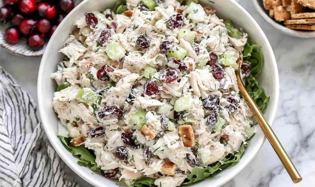 Cranberry chicken salad with pecans, apple, and dried cranberries in a white bowl
